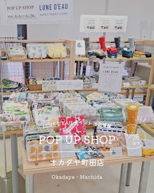 オカダヤ町田店のルネ・デュー北欧生地ポップアップ会場と、白い花柄やデイジー柄など色とりどりの北欧デザイン生地、ポーチ
