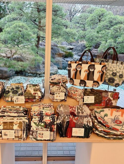 スウェーデン・テキスタイル展のポスターと、特設ショップに並ぶ花柄や動物柄の北欧生地・カットクロス・バッグ・雑貨