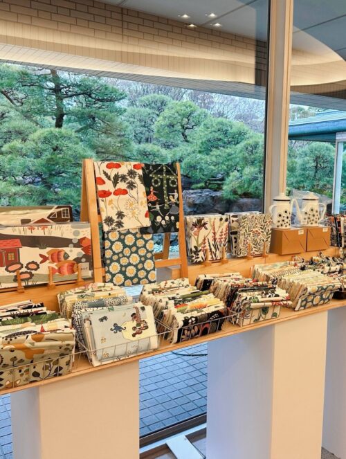 スウェーデン・テキスタイル展のポスターと、特設ショップに並ぶ花柄や動物柄の北欧生地・カットクロス・バッグ・雑貨