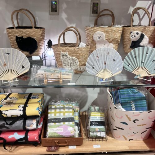 ストライプ地に猫やパンダの刺繍をあしらった扇子と、動物モチーフのカゴバッグが並ぶ店頭ディスプレイ