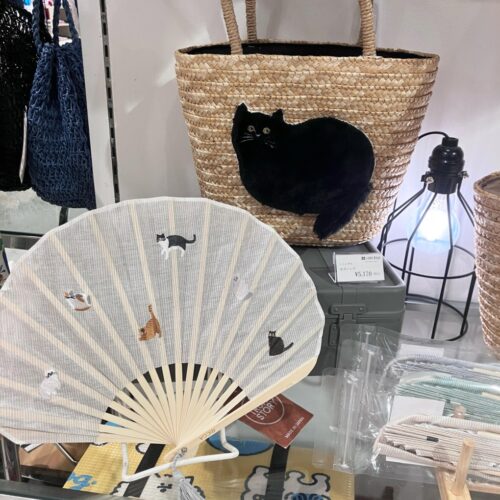 ストライプ地に猫やパンダの刺繍をあしらった扇子と、動物モチーフのカゴバッグが並ぶ店頭ディスプレイ