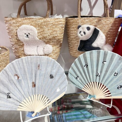 ストライプ地に猫やパンダの刺繍をあしらった扇子と、動物モチーフのカゴバッグが並ぶ店頭ディスプレイ