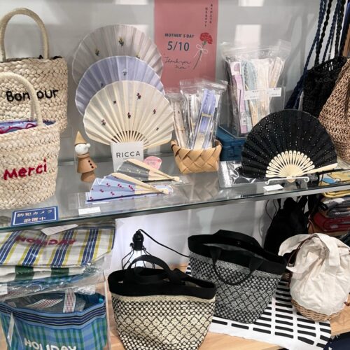 ストライプ地に猫やパンダの刺繍をあしらった扇子と、動物モチーフのカゴバッグが並ぶ店頭ディスプレイ
