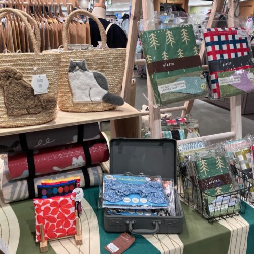 ストライプ地に猫やパンダの刺繍をあしらった扇子と、動物モチーフのカゴバッグが並ぶ店頭ディスプレイ