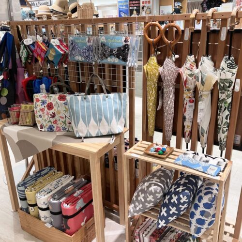 ストライプ地に猫やパンダの刺繍をあしらった扇子と、動物モチーフのカゴバッグが並ぶ店頭ディスプレイ