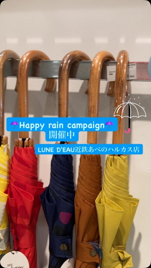 木製持ち手の北欧テイストな雨傘が並ぶ店頭。レッド・ネイビー・キャメル・イエローのドットやストライプ柄