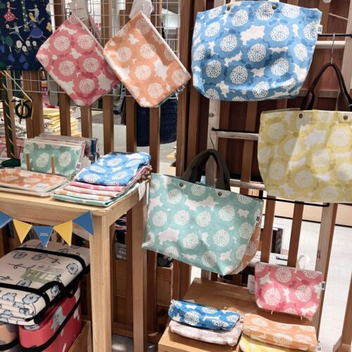 夏至祭のダンス柄ファブリックパネルやクッション、STUDIO HILLAクッキアの花柄トートとポーチを並べた北欧夏ディスプレイ