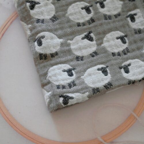 Studio Hillaのヒツジ柄「Baa」北欧生地。グレージュ地に白いヒツジが並ぶガーゼ生地と刺繍枠