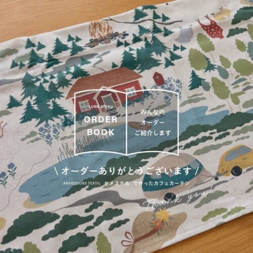 Arvidssons TextilのSemester(セメステル)柄カフェカーテン。生成り地に森・赤い小屋・湖などアウトドアを描いた北欧生地