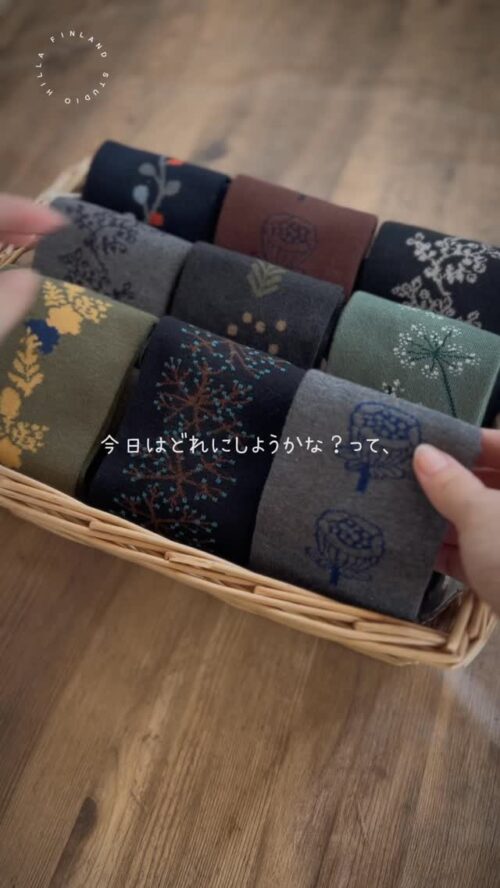 かごに並ぶスタジオヒッラの北欧柄ハイソックス。ネイビーやグレー、グリーンなど落ち着いた色に植物や花の模様が編み込まれている