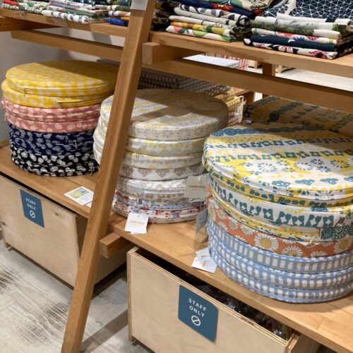 北欧柄のシートクッションが並ぶ店頭。ダーラナホースやフルーツ、街並み、ギンガムチェックなど色柄豊富なクッション