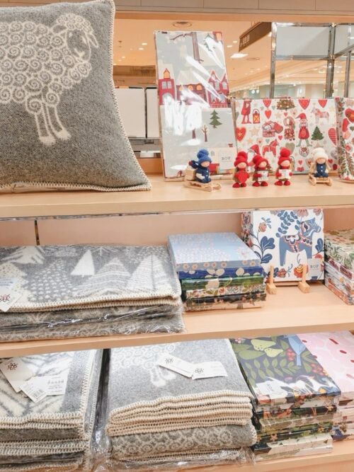 大丸札幌店のルネ・デュー出店ブースに並ぶ羊柄ウールブランケット、北欧植物柄トレー、くじらモチーフのカラフルな雑貨や花柄マグ