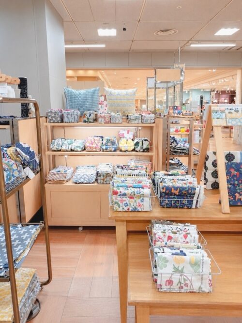 大丸札幌店のルネ・デュー出店ブースに並ぶ羊柄ウールブランケット、北欧植物柄トレー、くじらモチーフのカラフルな雑貨や花柄マグ