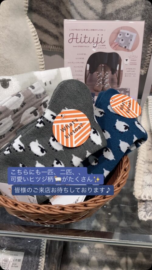 グレーとネイビーの地色に白いヒツジ柄が入ったキエトアソックスと、ウール素材のバーカーブランケットをかごに並べた北欧アイテム