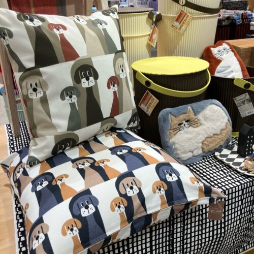 ふわふわ素材のネコモチーフクッションや湯たんぽカバー、イヌ柄クッション、モノトーン柄のテキスタイルを並べた北欧テイストのディスプレイ