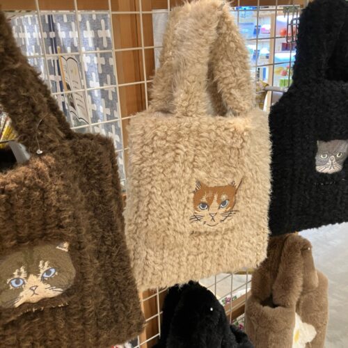 ふわふわ素材のネコモチーフクッションや湯たんぽカバー、イヌ柄クッション、モノトーン柄のテキスタイルを並べた北欧テイストのディスプレイ